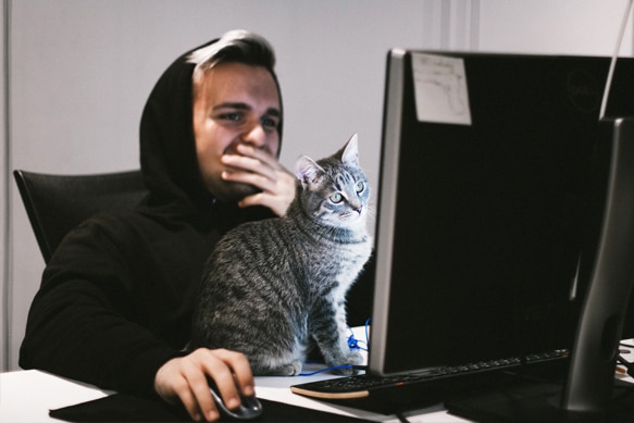 Young man wearing a hoodie looking upset as he reads a computer screen