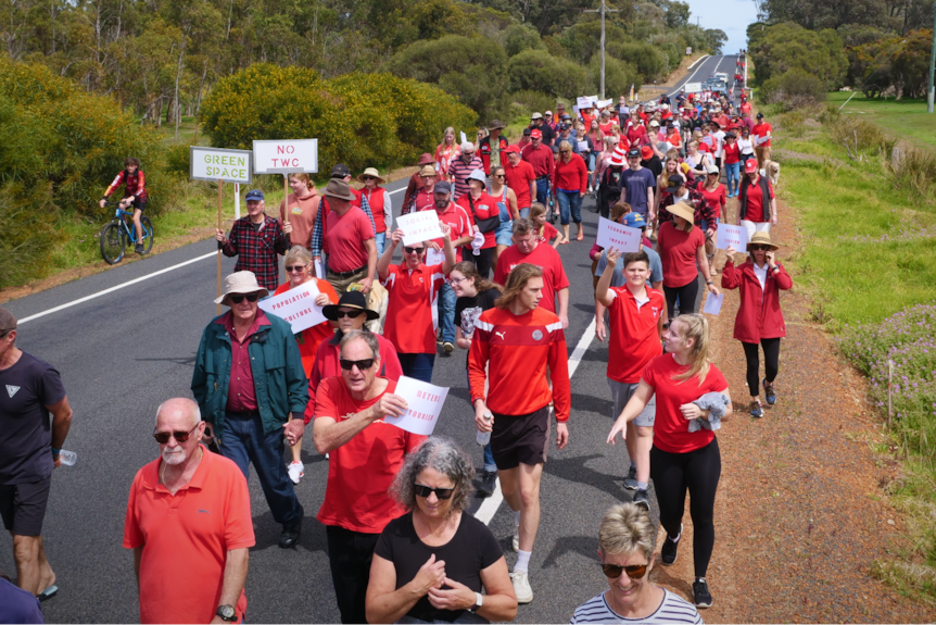 Dozens of people walking down a road, all wearing red.