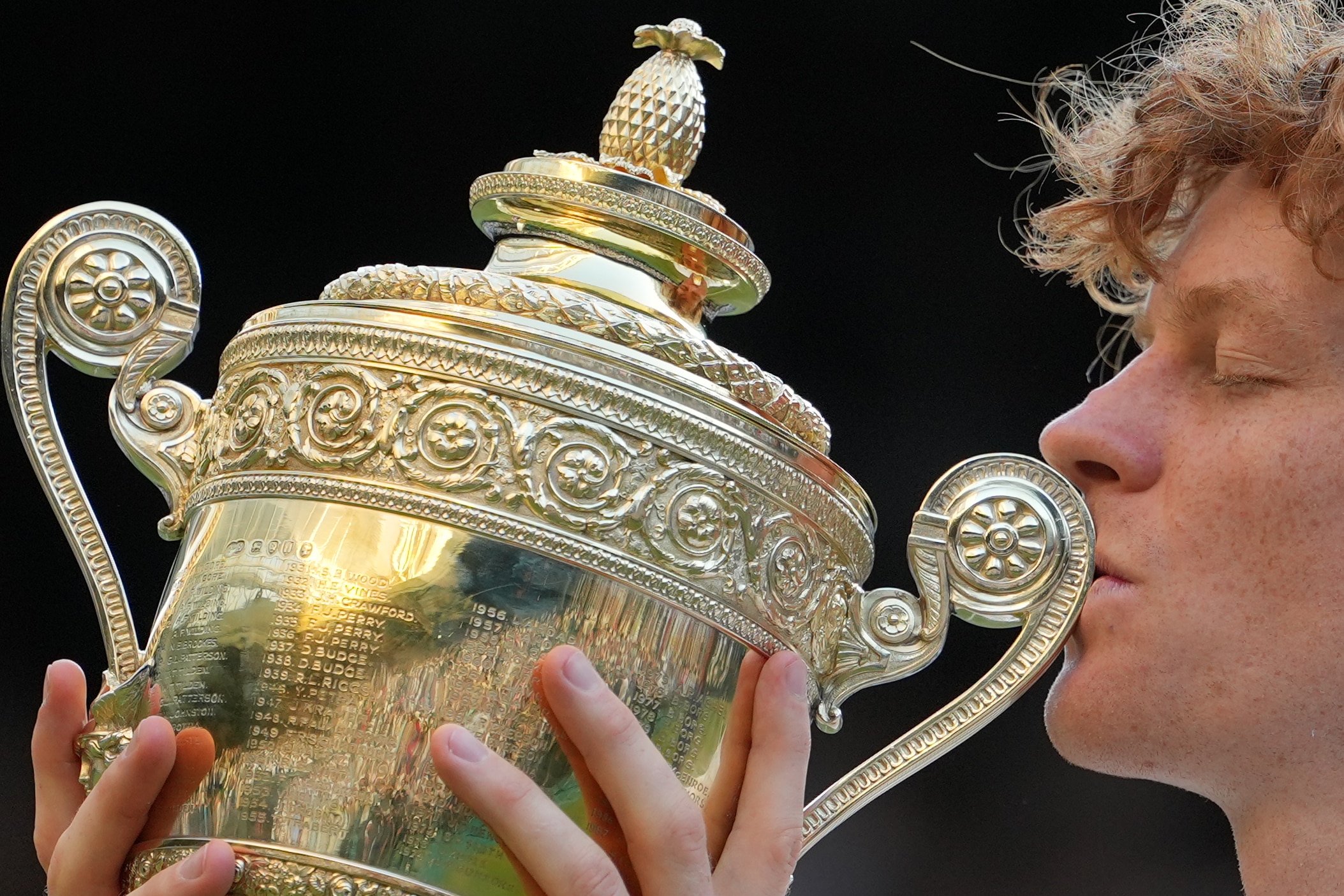 Jannik Sinner kissing a golden trophy.