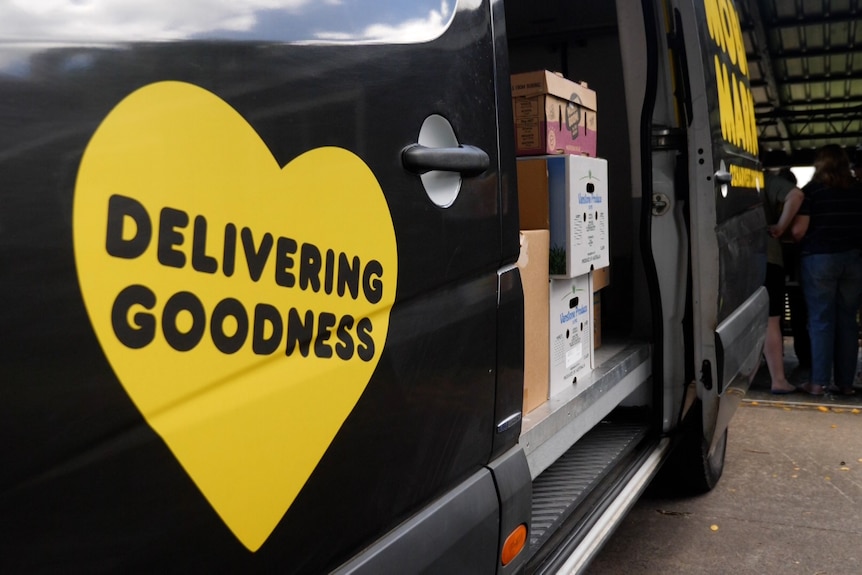 A black van with boxes inside the yellow heart saying 'delivering goodness'