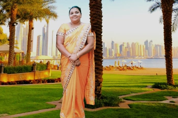 A woman in a traditional Indian dress standing in front of virtual tree.