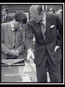 A black and white photo of Martin looking at a snake inside a container with Prince Phillip