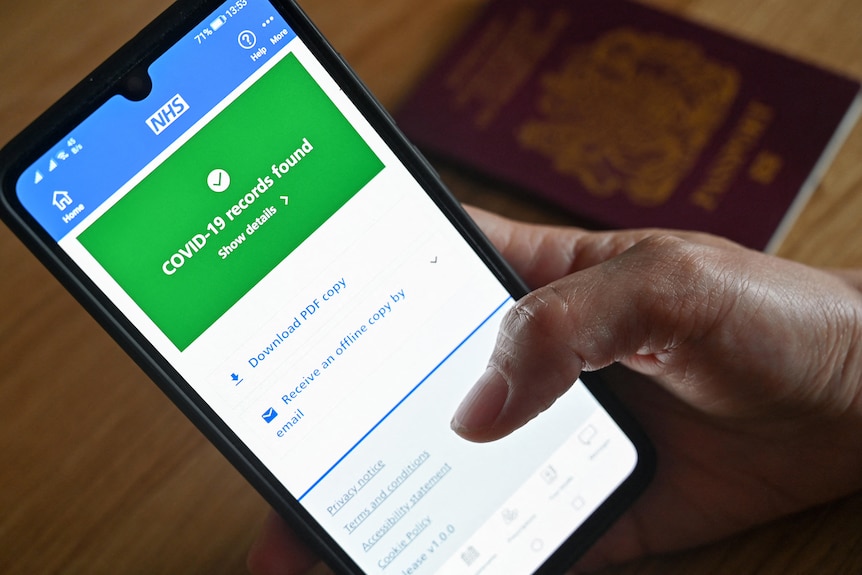 A person uses their thumb to scroll down a smartphone COVID vaccine passport app on a smart phone.