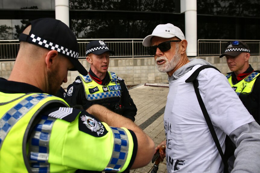 A man with a white beard yells at police officers.