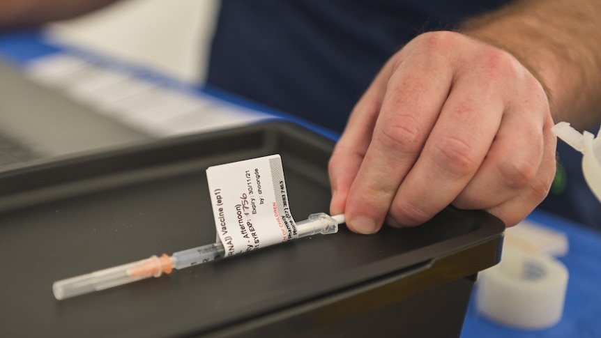 A health worker at NRL Grand Final pop-up Covid-19 vaccination hub at Lang Park reaches for a vaccine.