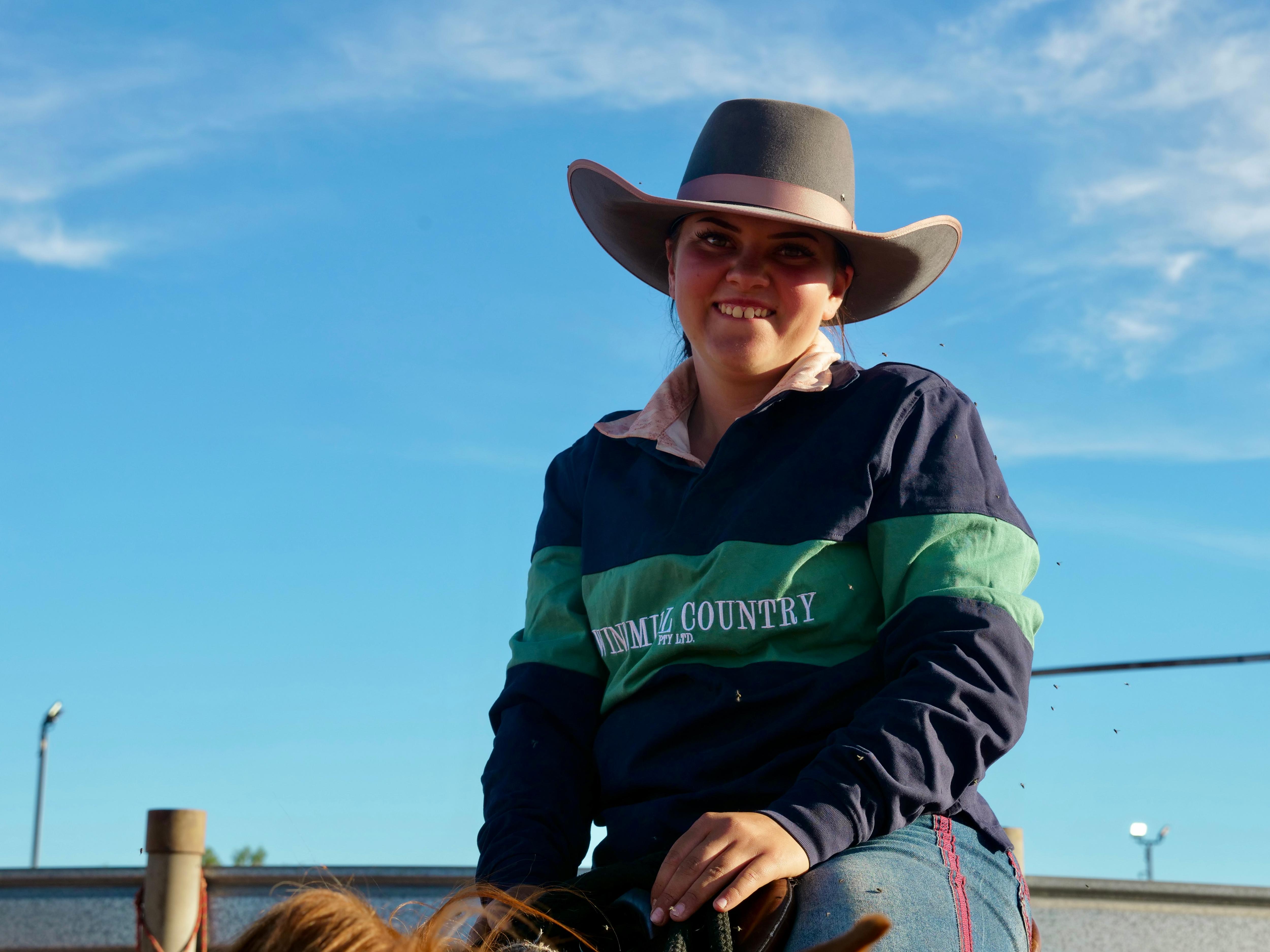 a girl with a grey hat and green and blue jumper smiling 