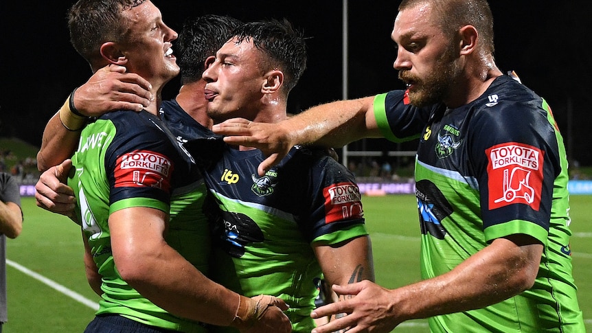 An NRL player is hugged by teammates after saving a try.