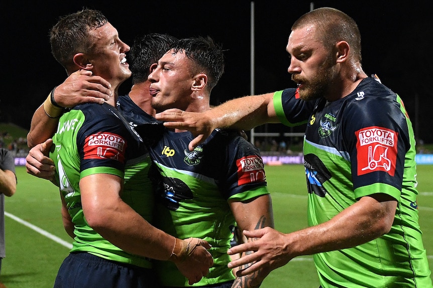 An NRL player is hugged by teammates after saving a try.