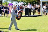 Prince Charles walks across the lawn with a wreath in his hand