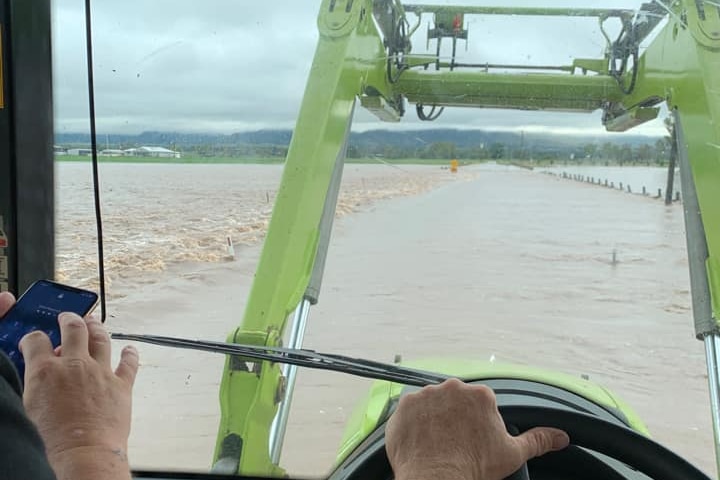 A tractor driving through flood water.
