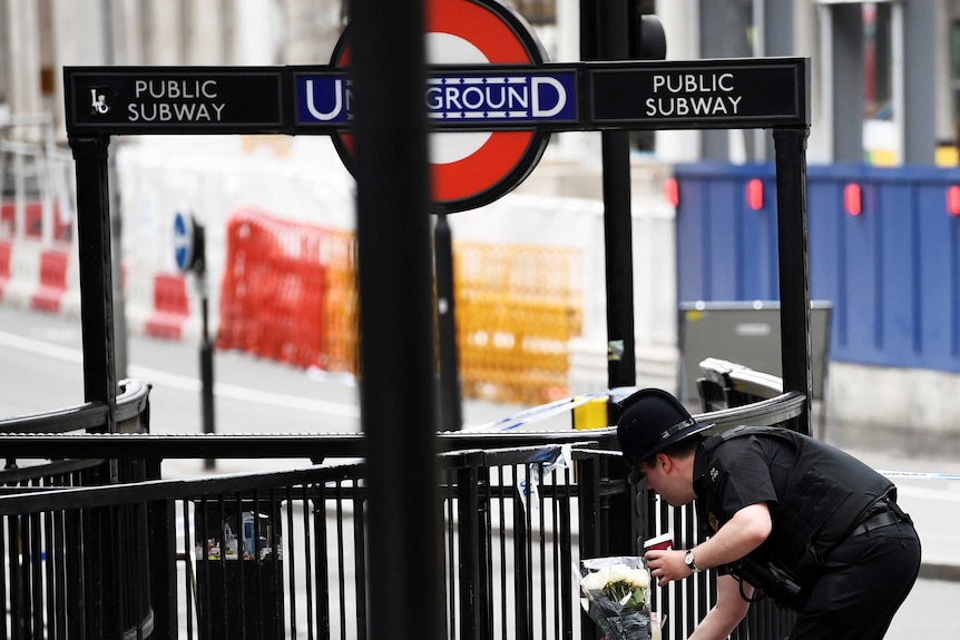 A police officer leaves flowers at London Bridge, near the entrance of the underground subway