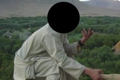 A man in traditional Afghan clothing sitting on a mountain.