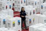 A woman in the middle of ballot boxes pictured from above.