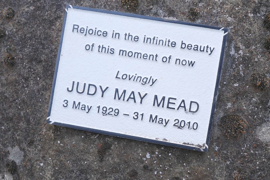 A small memorial plaque on a rock for Judy May Mead who died 2010.