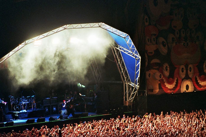 A long-distance shot of the crowd and the stage during Limp Bizkit's set, with Fred Durst visible in a red cap
