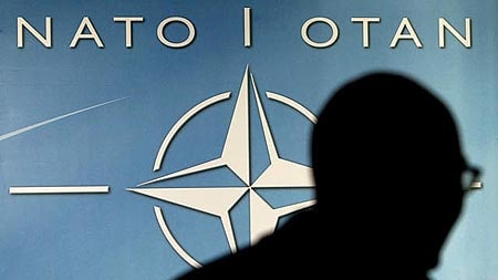 Man walking in front of NATO banner