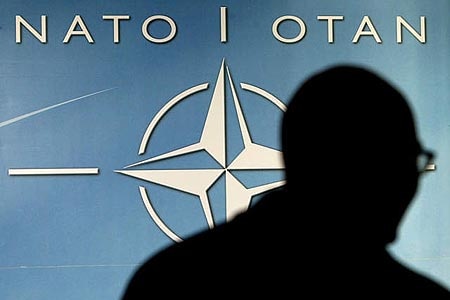 Man walking in front of NATO banner