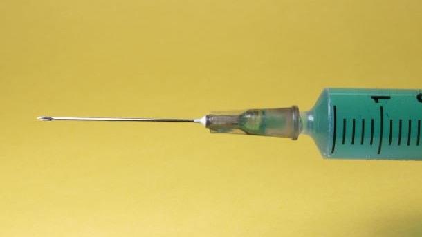 Picture of a syringe against a yellow background 