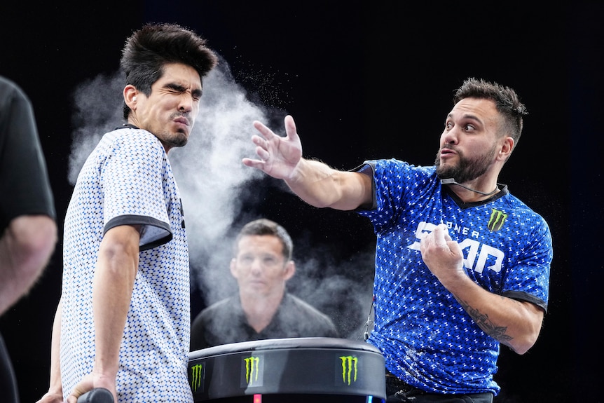 A man is pictured getting a slap in the face from another man as a cloud of white dust arises from it.