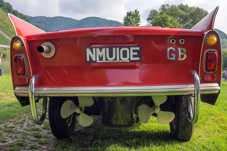 The rear of a red amphibious car showing two propellers and a number plate.