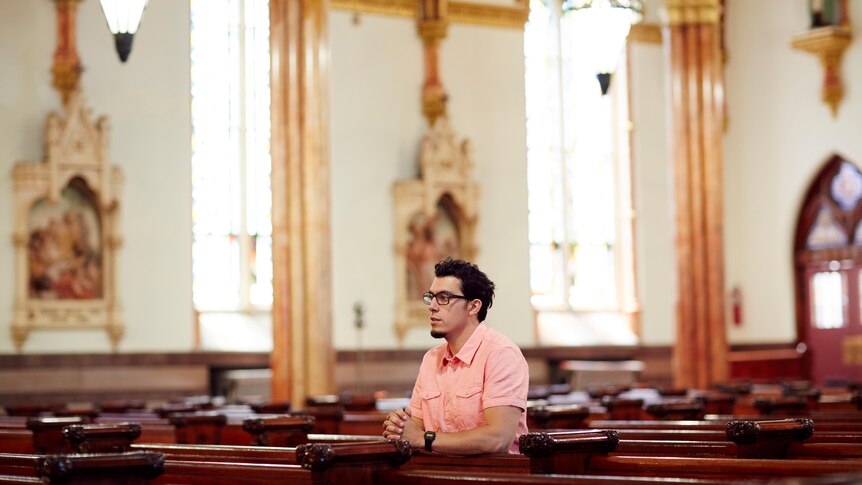 Young hispanic american man kneeling in church pew
