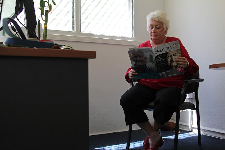 A photo of Sue Shearer reading a magazine in her office.