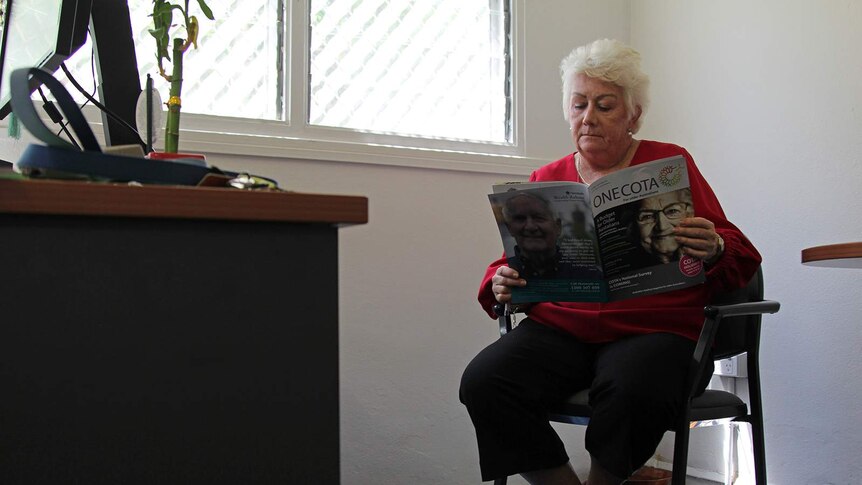 A photo of Sue Shearer reading a magazine in her office.