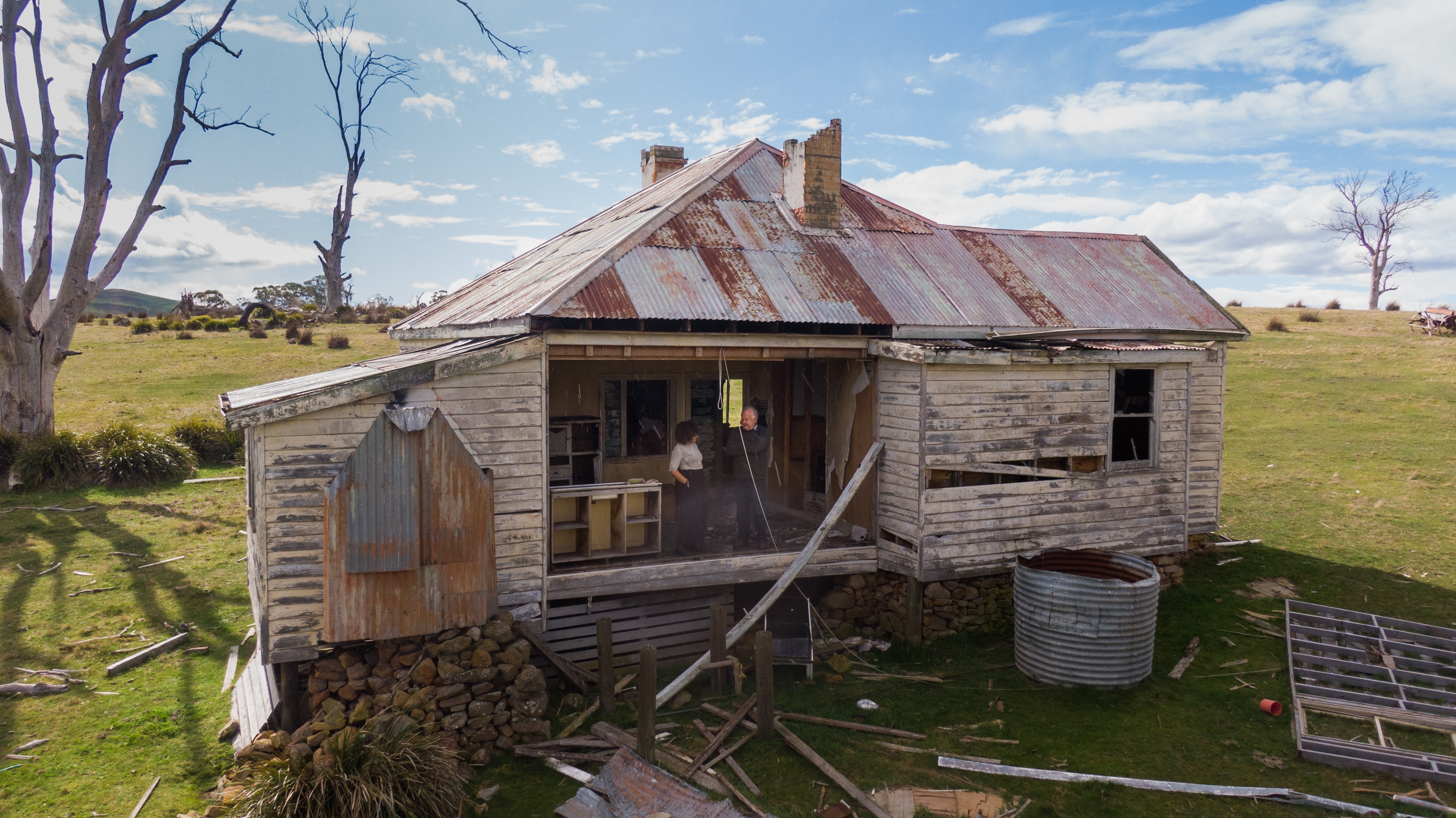 Two people stand in kitchen of house missing wall