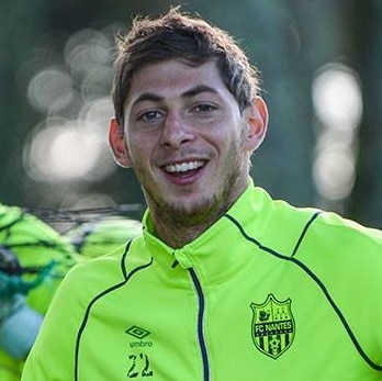 A young man smiling and facing the camera, wearing a bright yellow sport jacket