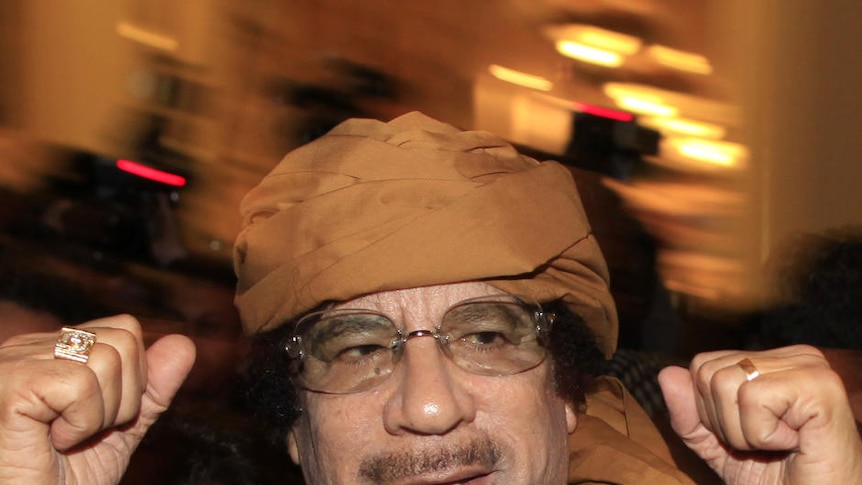 Libya's leader Moamar Gaddafi pumps his fists as he arrives at a hotel to meet the media in Tripoli.