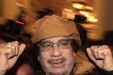 Libya's leader Moamar Gaddafi pumps his fists as he arrives at a hotel to meet the media in Tripoli.