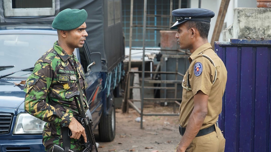 A special task force officer speaks with an official outside the home of Inshaf Ibrahim