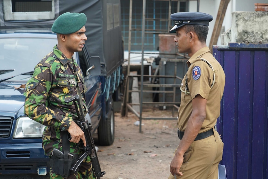 A special task force officer speaks with an official outside the home of Inshaf Ibrahim