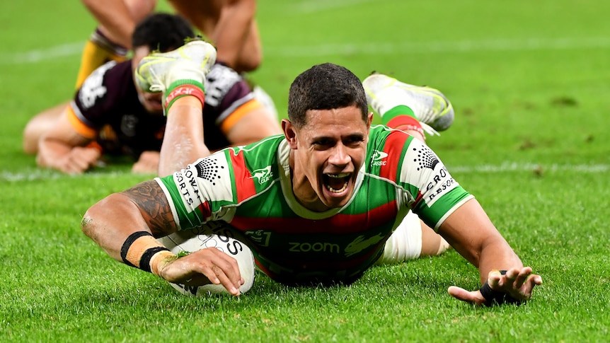 A South Sydney NRL player lies on the ground after scoring a try against the Brisbane Broncos.