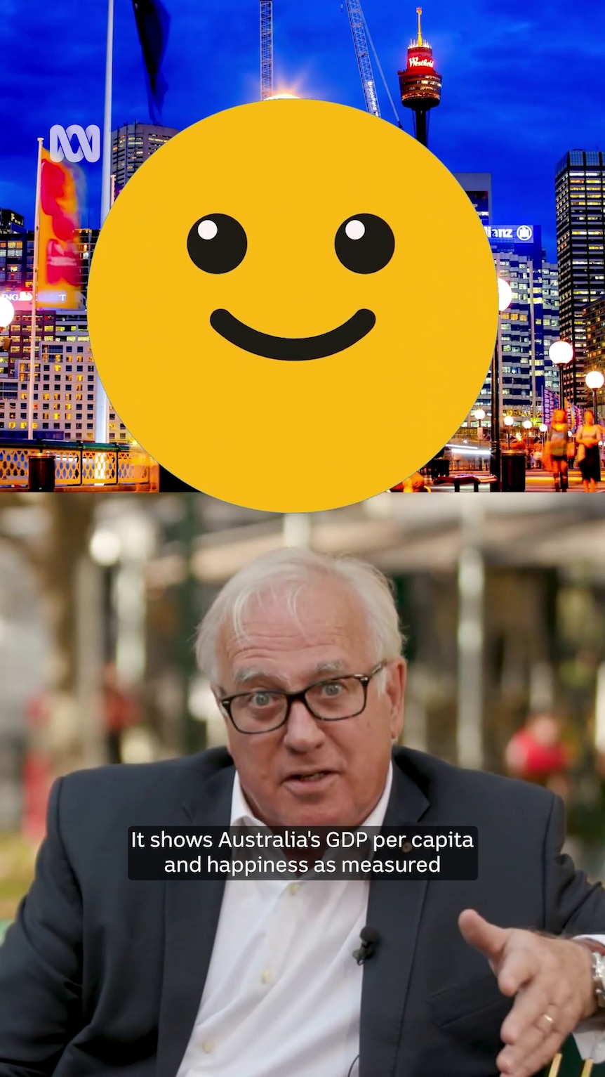 A white man with white hair in a white shirt and suit jacket gesticulates under a yellow happy face emoji