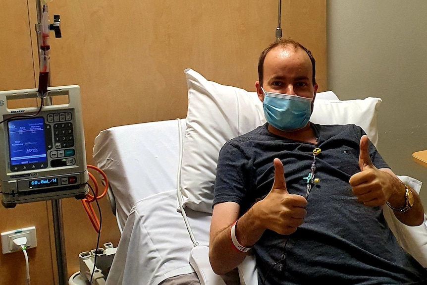 Duncan Pegg in hospital bed with thumbs up as he receives blood transfusion.