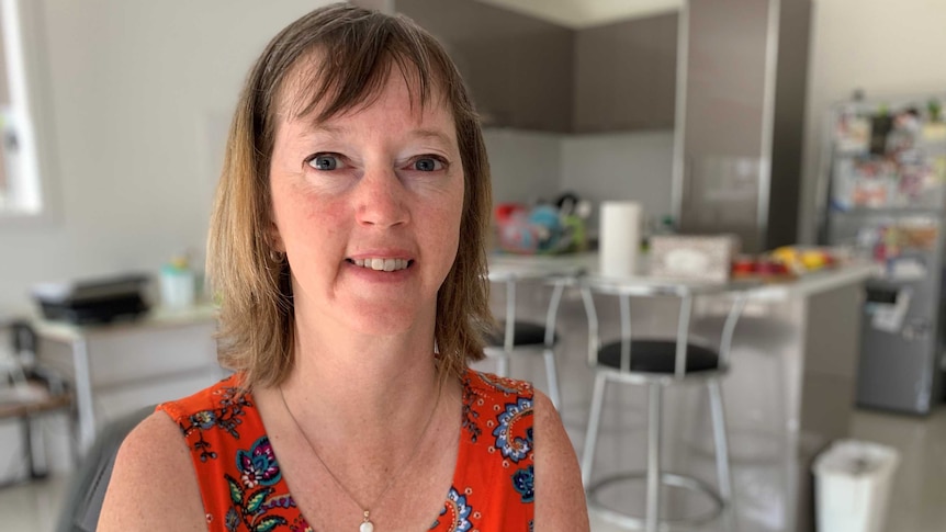 A middle-aged woman in her kitchen looking at the camera