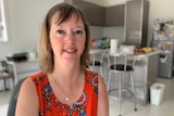 A middle-aged woman in her kitchen looking at the camera