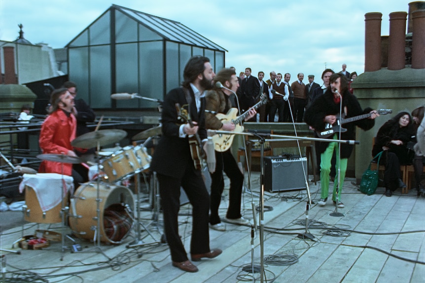 A photo of the Beatles band playing on a rooftop beneath grey skies