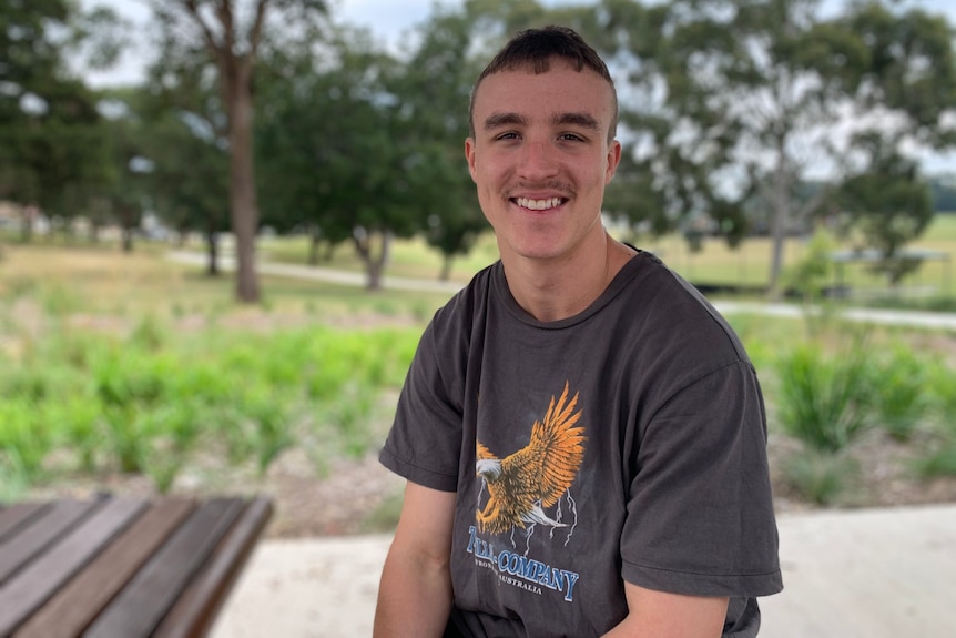 A young man sitting and smiling. 