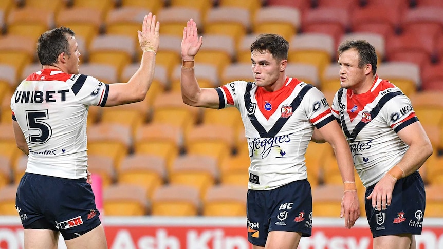 Sydney Roosters Kyle Flanagan and Brett Morris high-five. Josh Morris looks on during an NRL game against the Brisbane Broncos.