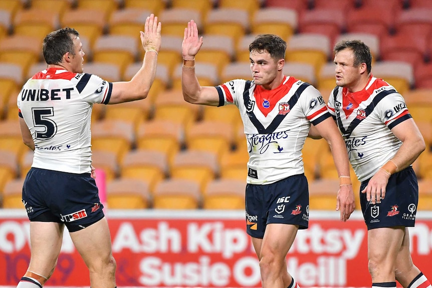 Sydney Roosters Kyle Flanagan and Brett Morris high-five. Josh Morris looks on during an NRL game against the Brisbane Broncos.