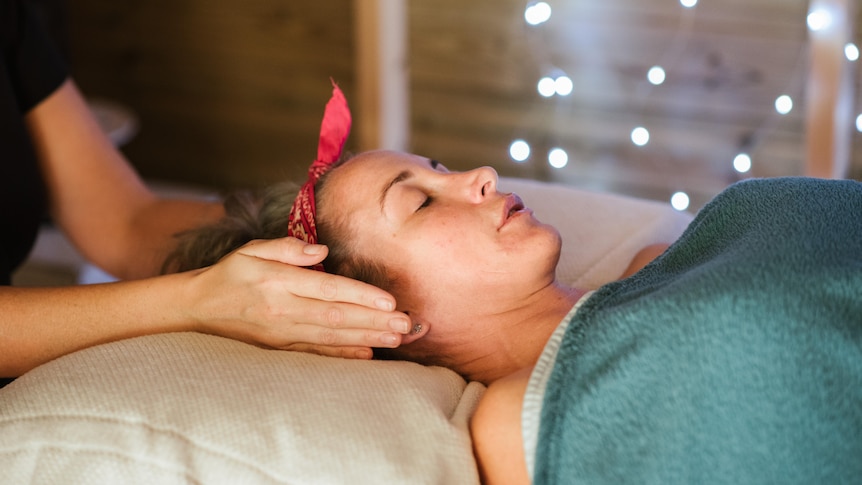 Woman lays on massage table getting a facial in a story about lymphatic drainage facial massages and do they work