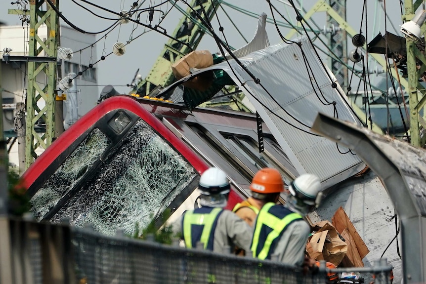 A damaged trains sits derailed after a collision with a truck.