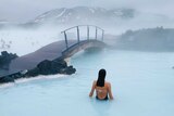 Woman in bathing suit standing in Iceland's blue lagoon for a story about travel destinations to visit if you love winter.
