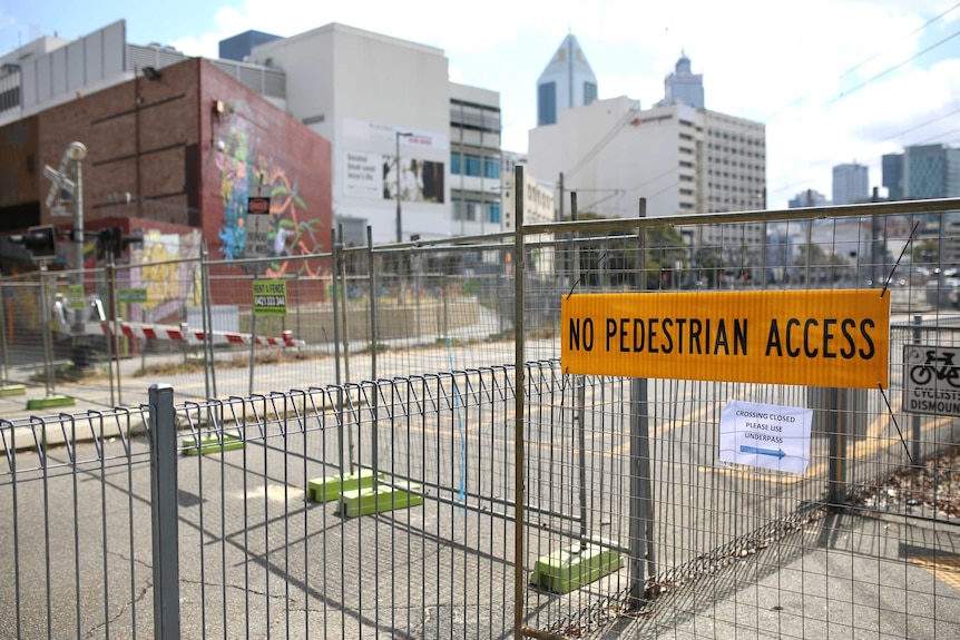 A temporary fence near the train line reads no pedestrian access