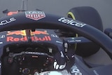 Vision from inside Max Verstappen's car shows him raising his right middle finger at a car ahead of him