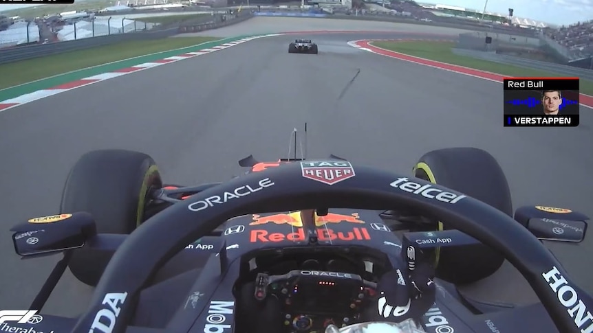 Vision from inside Max Verstappen's car shows him raising his right middle finger at a car ahead of him