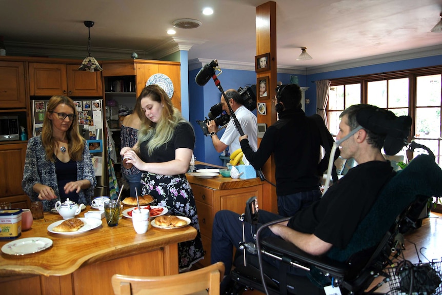 Cameraman and sound recordist filming in kitchen around Yerbury, wife and daughter.