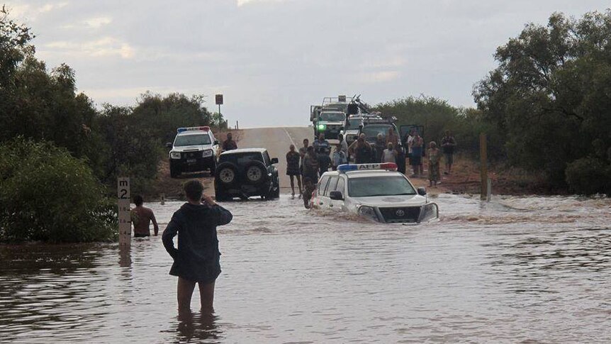 A police vehicle attempts to cross the flooded Minilya-Exmouth road near Exmouth